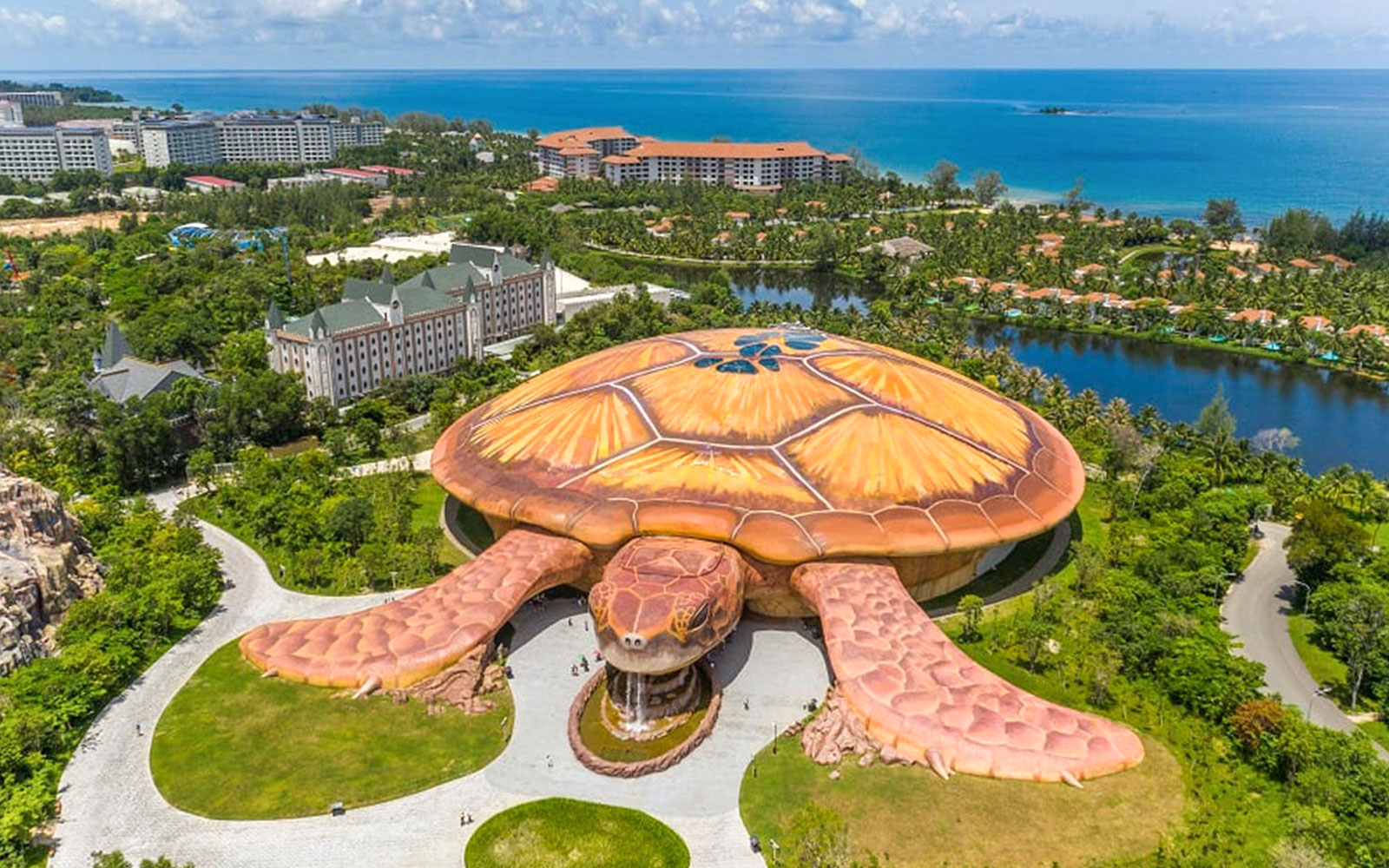 Aerial view of turtle-shaped building at VinWonders, Phu Quoc, with ocean in background.