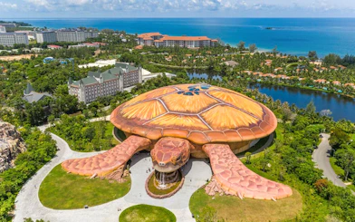 Aerial view of turtle-shaped building at VinWonders, Phu Quoc, with ocean in background.