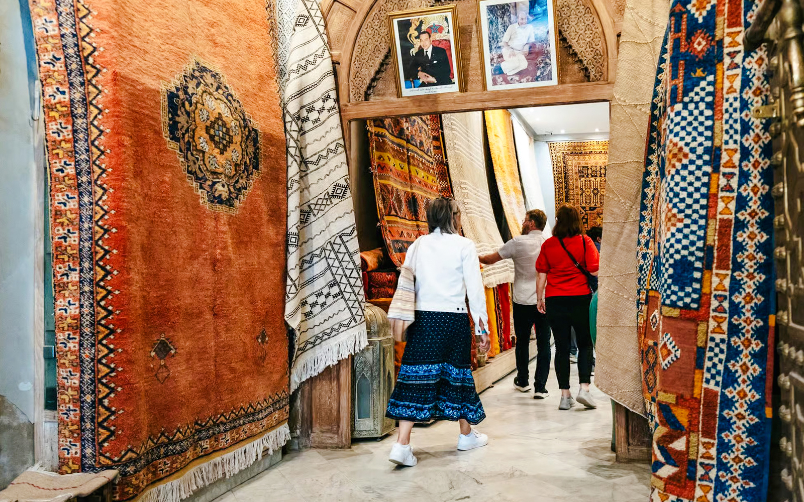 Visitors exploring vibrant rugs in Marrakech souk during a private shopping tour.