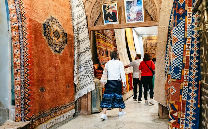 Visitors exploring vibrant rugs in Marrakech souk during a private shopping tour.
