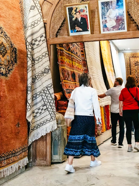 Visitors exploring vibrant rugs in Marrakech souk during a private shopping tour.