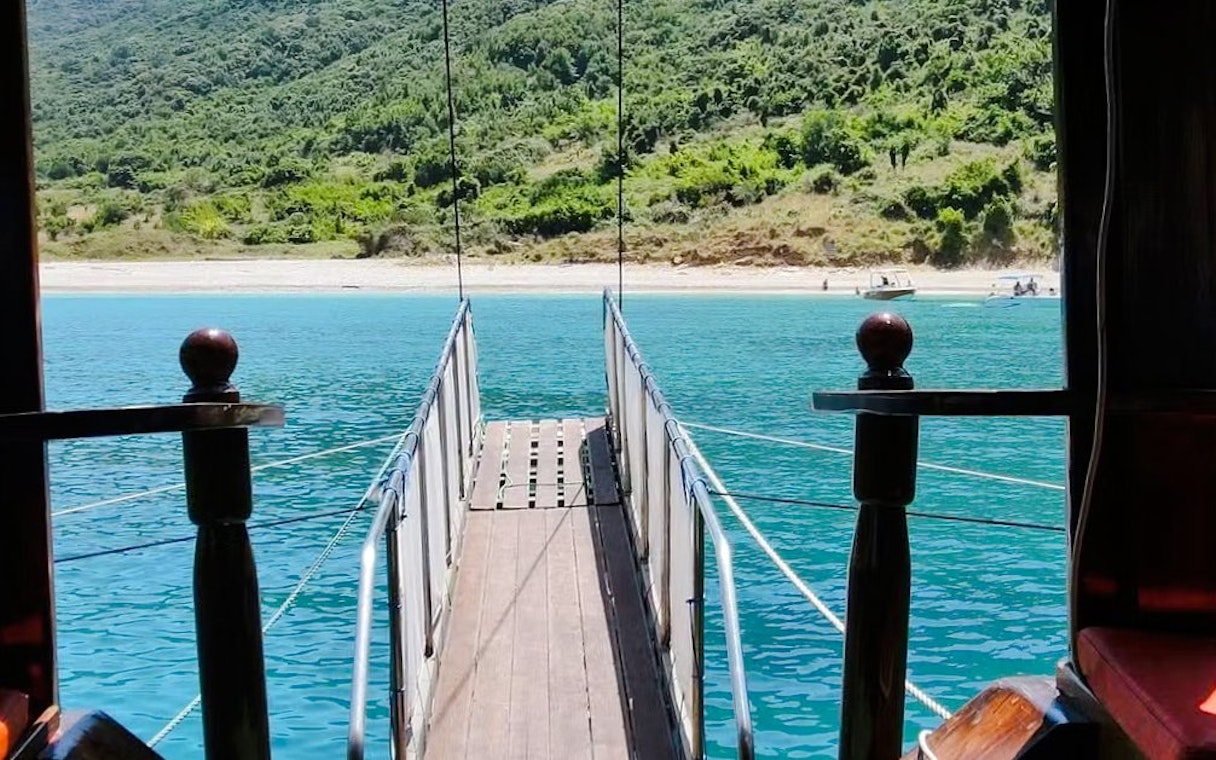 Pirate ship gangway leading to Saranda beach with turquoise water.