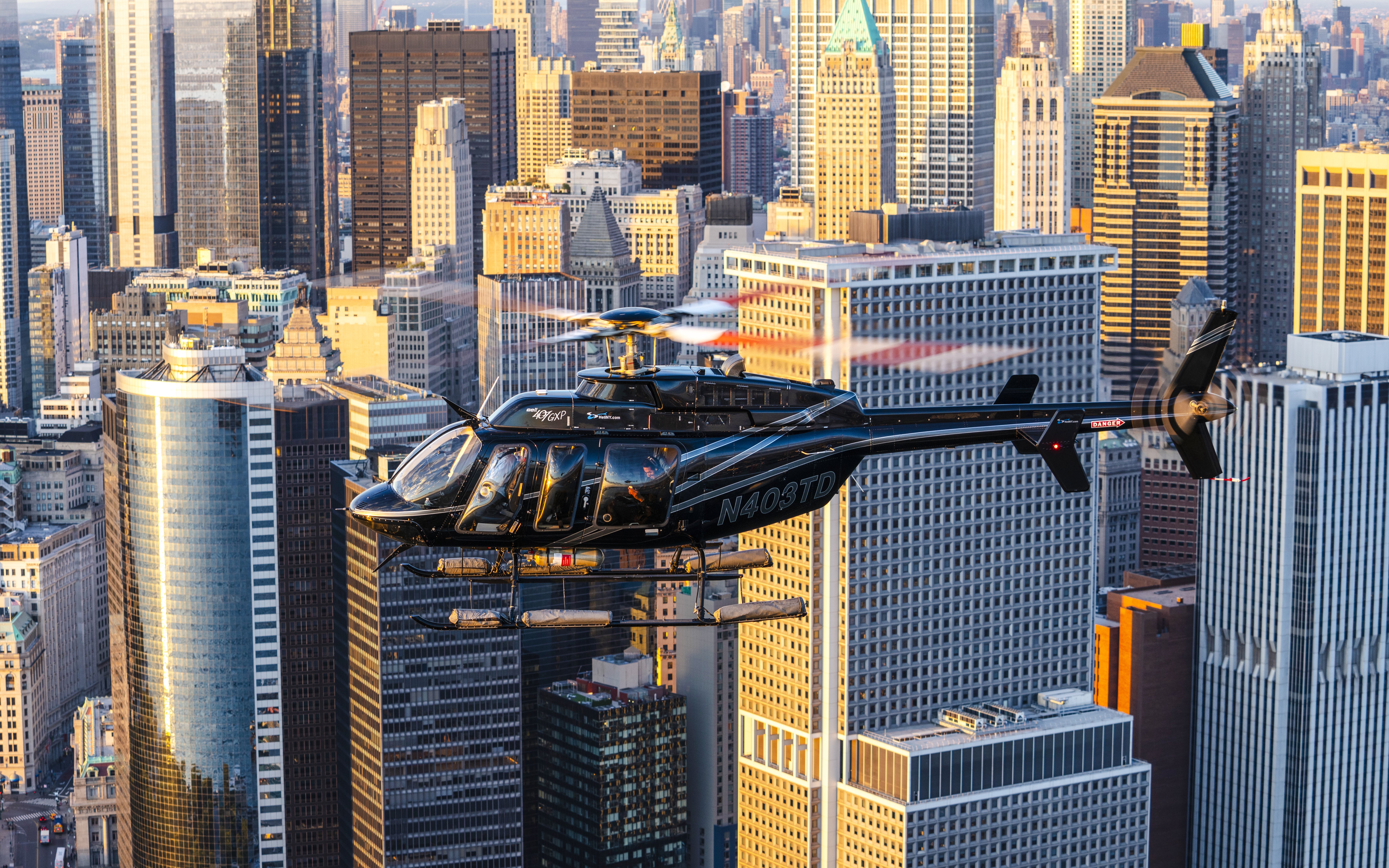 Helicopter flying over New York City skyline during sunset.