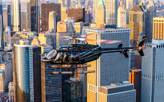 Helicopter flying over New York City skyline during sunset.