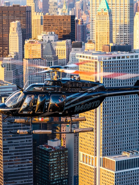 Helicopter flying over New York City skyline during sunset.