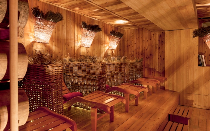Relaxation area with wooden loungers and wicker baskets at QC Terme Pré Saint Didier.