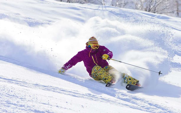 Skier carving through snow at Tomamu Ski Resort, Japan.