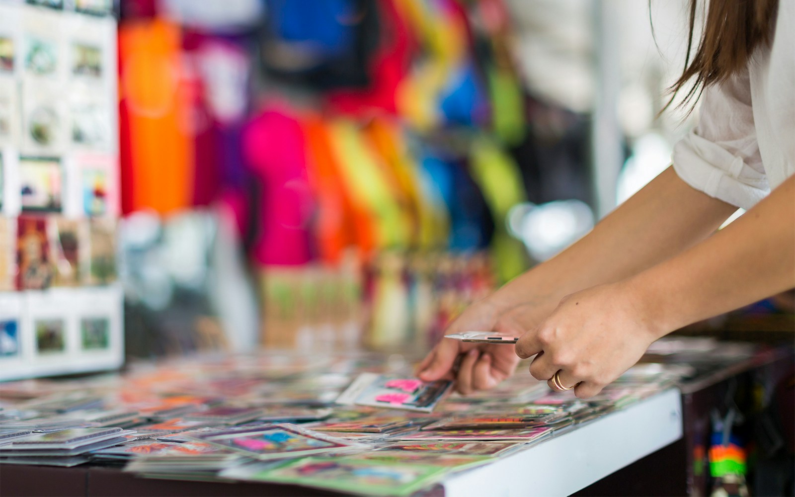 Person browsing colorful postcards at a market stall.