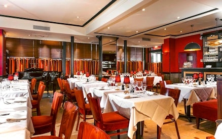 Elegant dining room setup for Bel Canto Opera Dinner Show with tables and a piano.