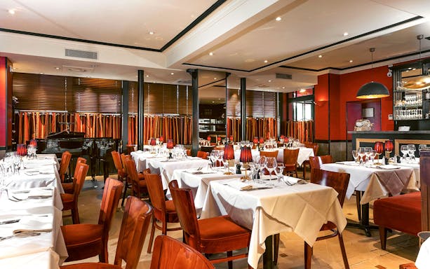 Elegant dining room setup for Bel Canto Opera Dinner Show with tables and a piano.