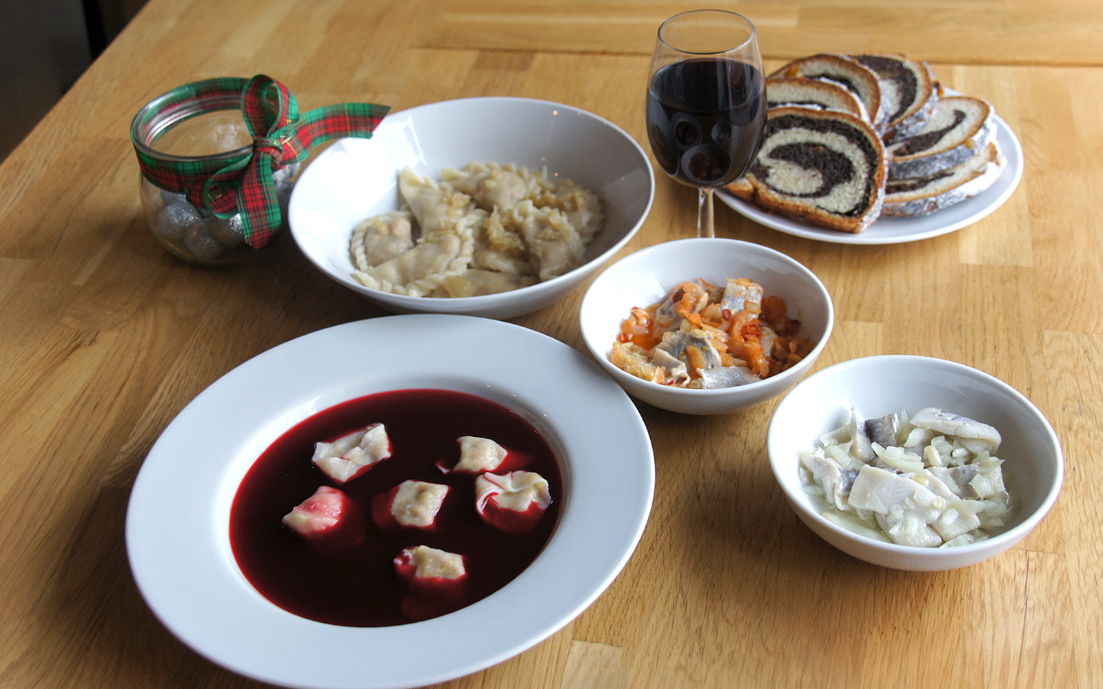 Polish dumplings with beet soup and assorted dishes on a wooden table.