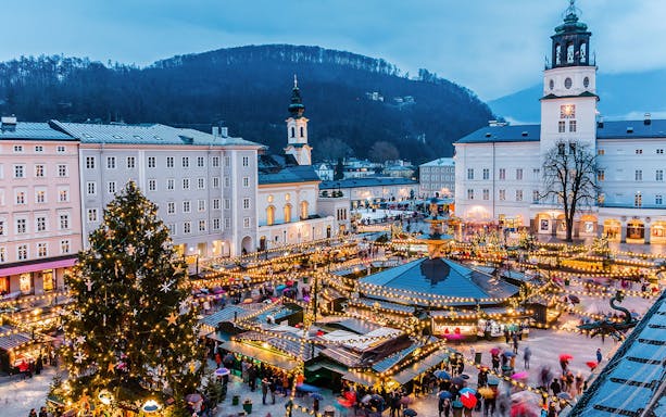 Salzburg Christmas market with festive lights and Fortress Hohensalzburg in the background.