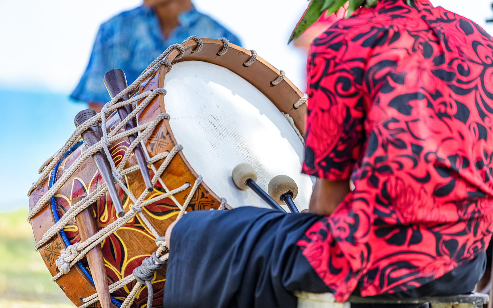 Man playing Pahu drum at a Hawaiian luau.
