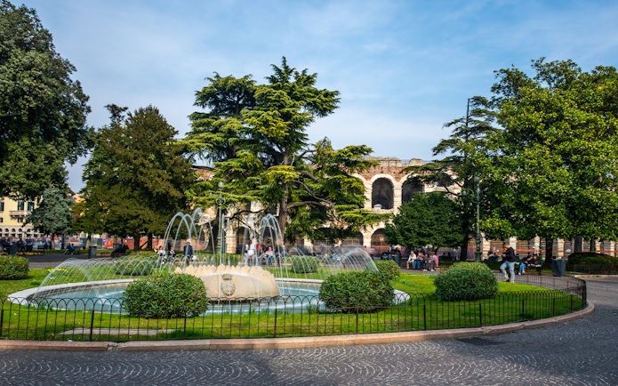 Verona Arena with fountain and trees in foreground, Italy.