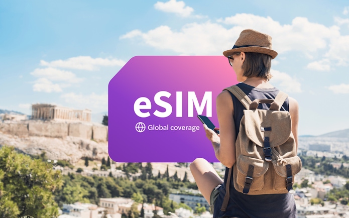 Traveler using smartphone with eSIM in Athens, Greece, overlooking the Acropolis.