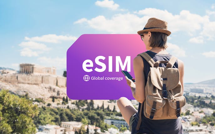 Traveler using smartphone with eSIM in Athens, Greece, overlooking the Acropolis.
