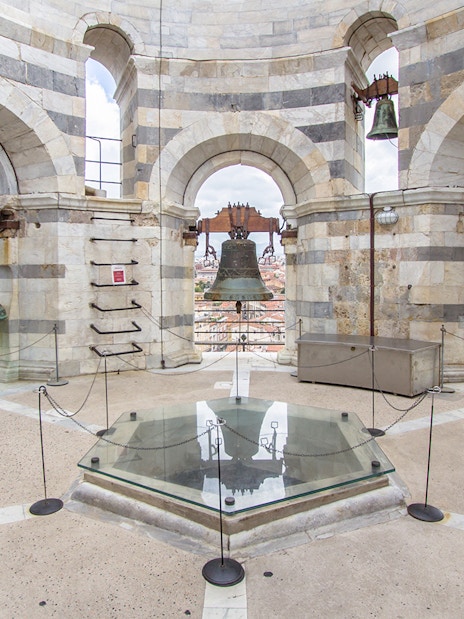 Church bells atop the Leaning Tower of Pisa, Italy, with city view.
