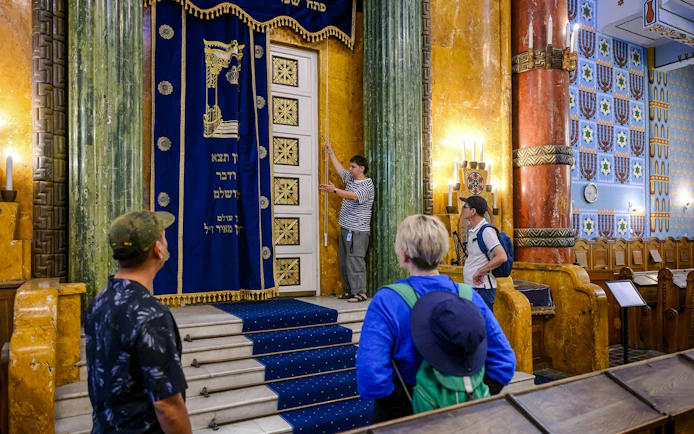 Guests observing ornate interior of Kazinczy Synagogue, Budapest.