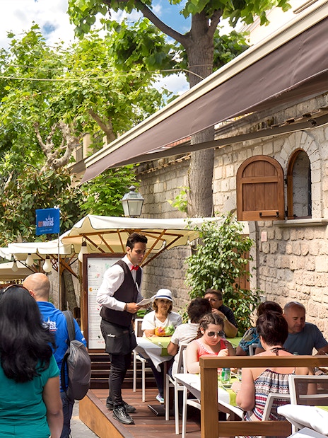 Street cafe in Positano with tourists dining and exploring, part of a guided day trip from Rome.