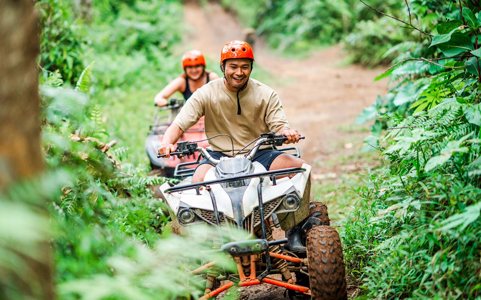 Couple riding ATVs through lush forest trail in Bali.