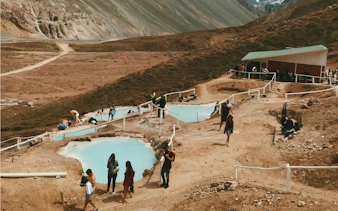 Visitors enjoying Termas Colina hot springs in Chile's mountainous landscape.