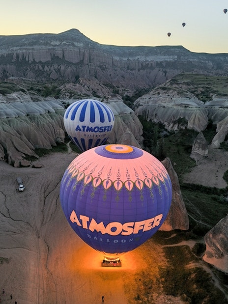 Hot air balloons from Atmosfer soaring over Cappadocia's unique rock formations at sunrise.