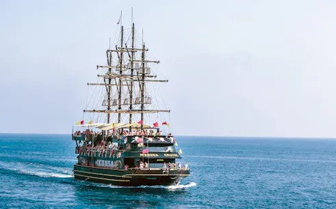 Pirate-themed boat sailing from Kemer to Phaselis Bay with passengers on deck.