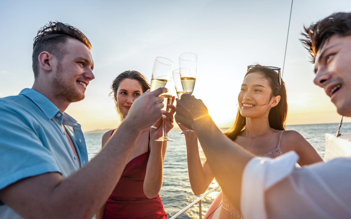 Friends toasting with prosecco on a sunset cruise on Gdansk River.