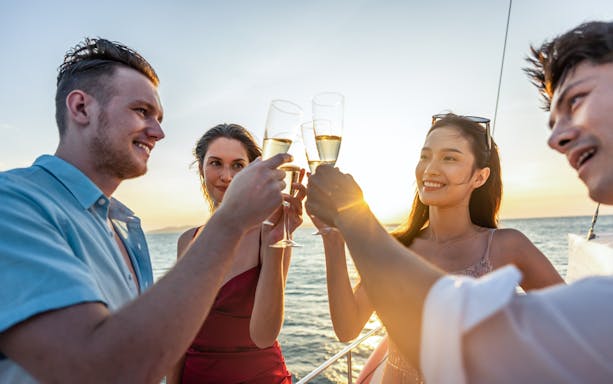 Friends toasting with prosecco on a sunset cruise on Gdansk River.