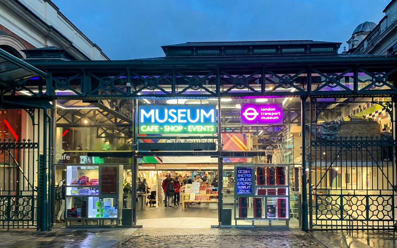 Entrance to London Transport Museum with neon signs and visitors inside.