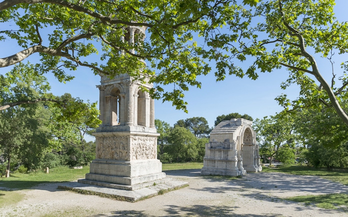 Glanum Archaeological Site entrance with Roman ruins and lush greenery.