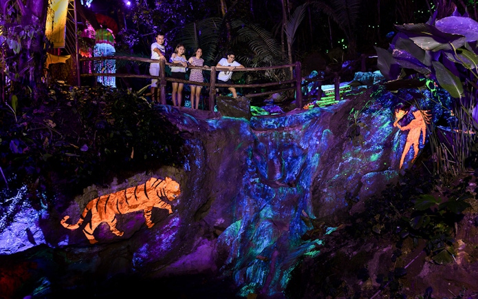 Visitors observing illuminated rock art at Sunway Lost World of Tambun, Malaysia.