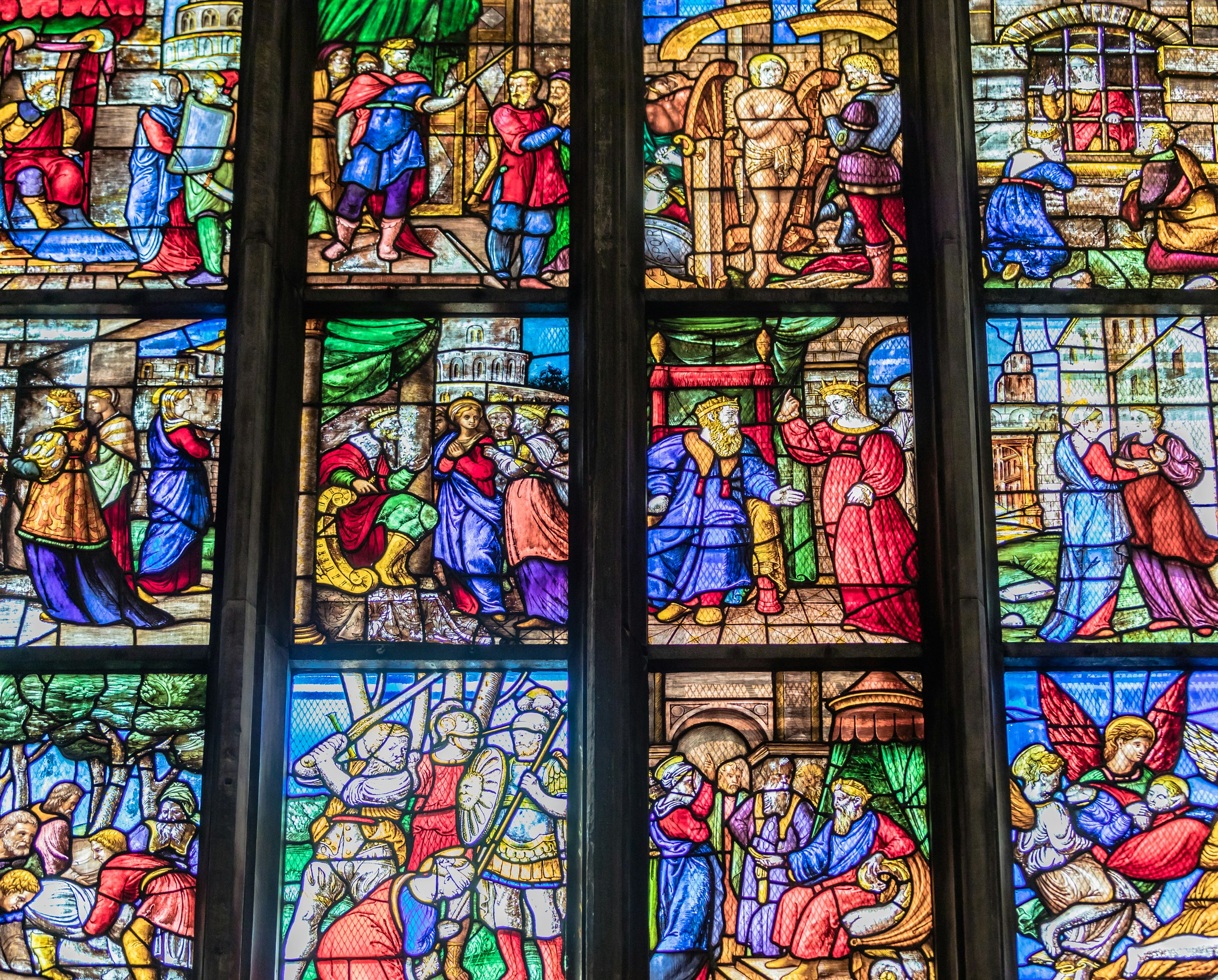 Stained glass window depicting biblical scenes at Milan Duomo Cathedral museum.