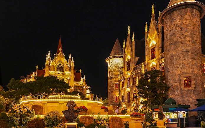 Catholic Cathedral and stone castle illuminated at night in Ba Na Hills Park, Da Nang, Vietnam.