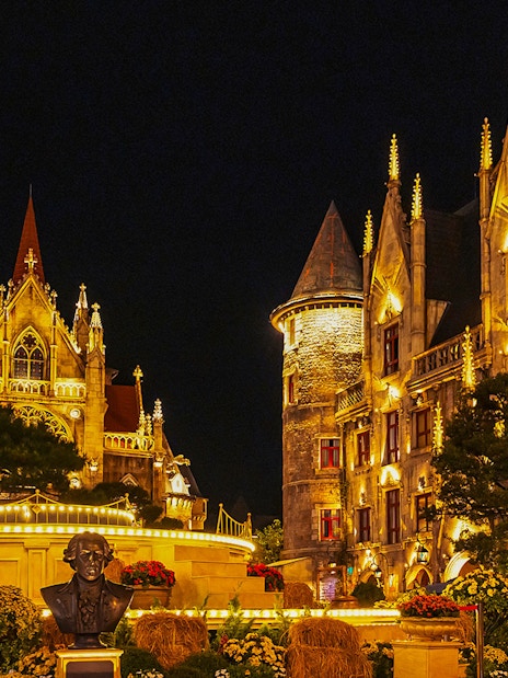 Catholic Cathedral and stone castle illuminated at night in Ba Na Hills Park, Da Nang, Vietnam.