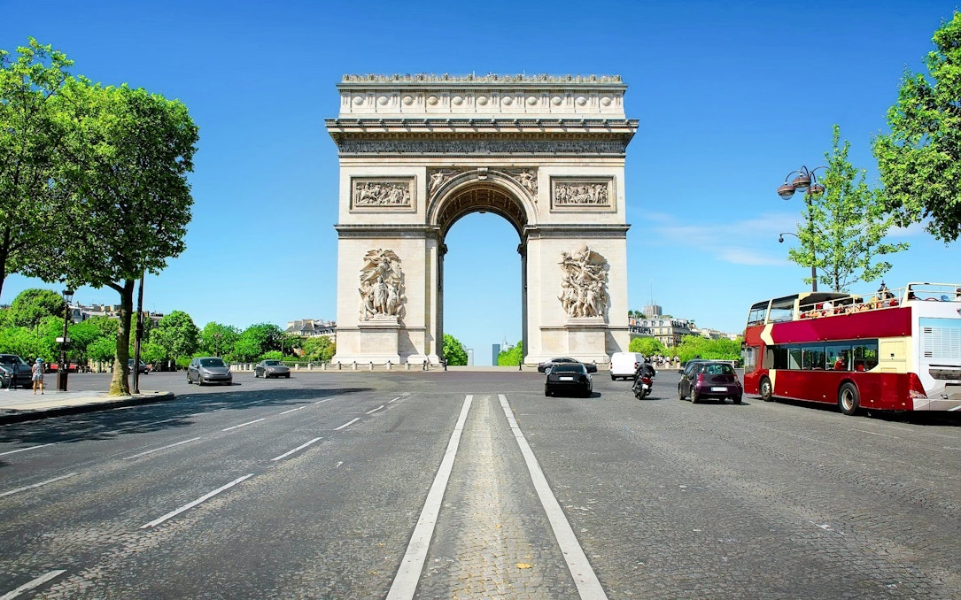 Arc de Triomphe in Paris with nearby tour bus, ideal for Ladurée tea time experience.