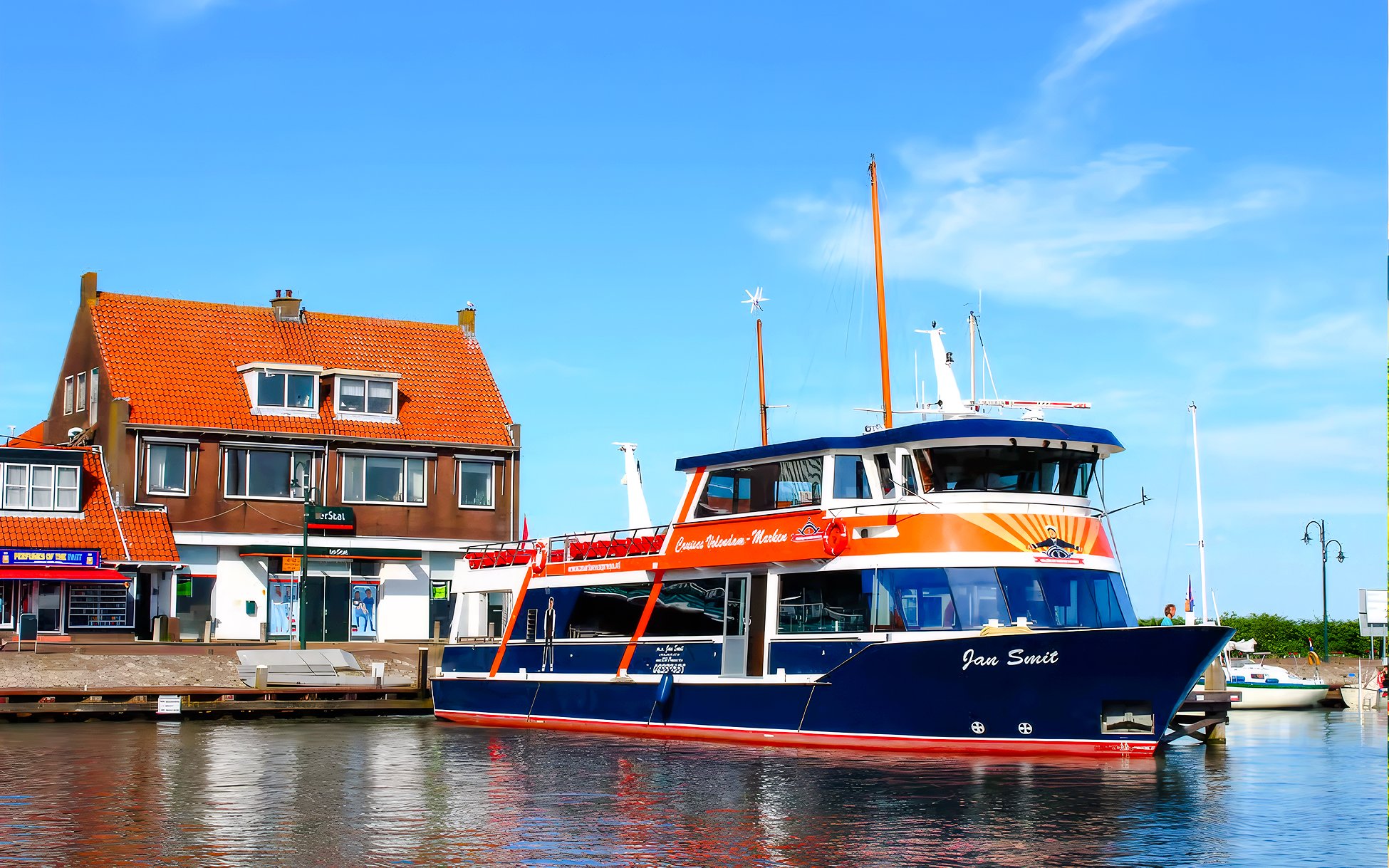 Tour boat docked at Marken with traditional Dutch house in the background.