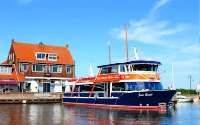 Tour boat docked at Marken with traditional Dutch house in the background.
