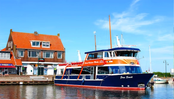 Tour boat docked at Marken with traditional Dutch house in the background.