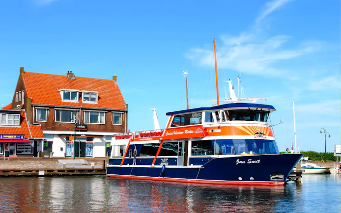 Tour boat docked at Marken with traditional Dutch house in the background.