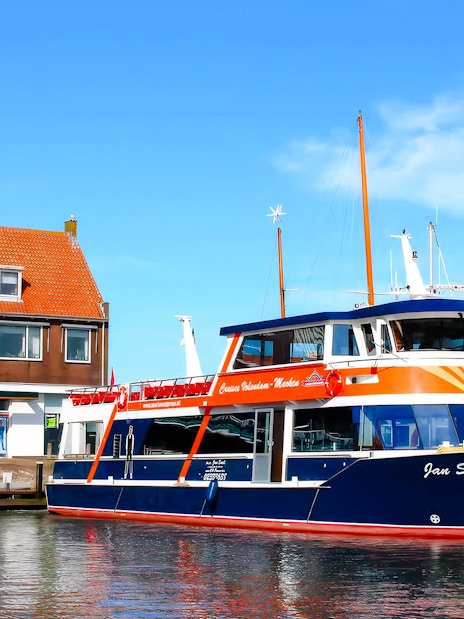 Tour boat docked at Marken with traditional Dutch house in the background.