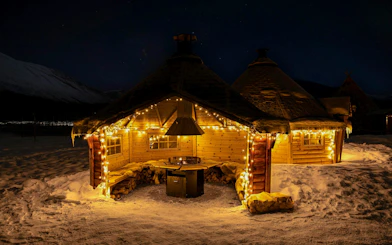Wooden hut with lights in snowy Tromso, Norway, near reindeer feeding area.