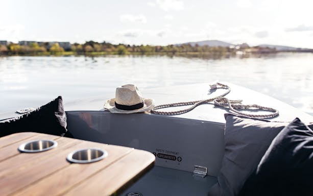 Self-drive electric picnic boat with hat and cushions on Sydney harbor.