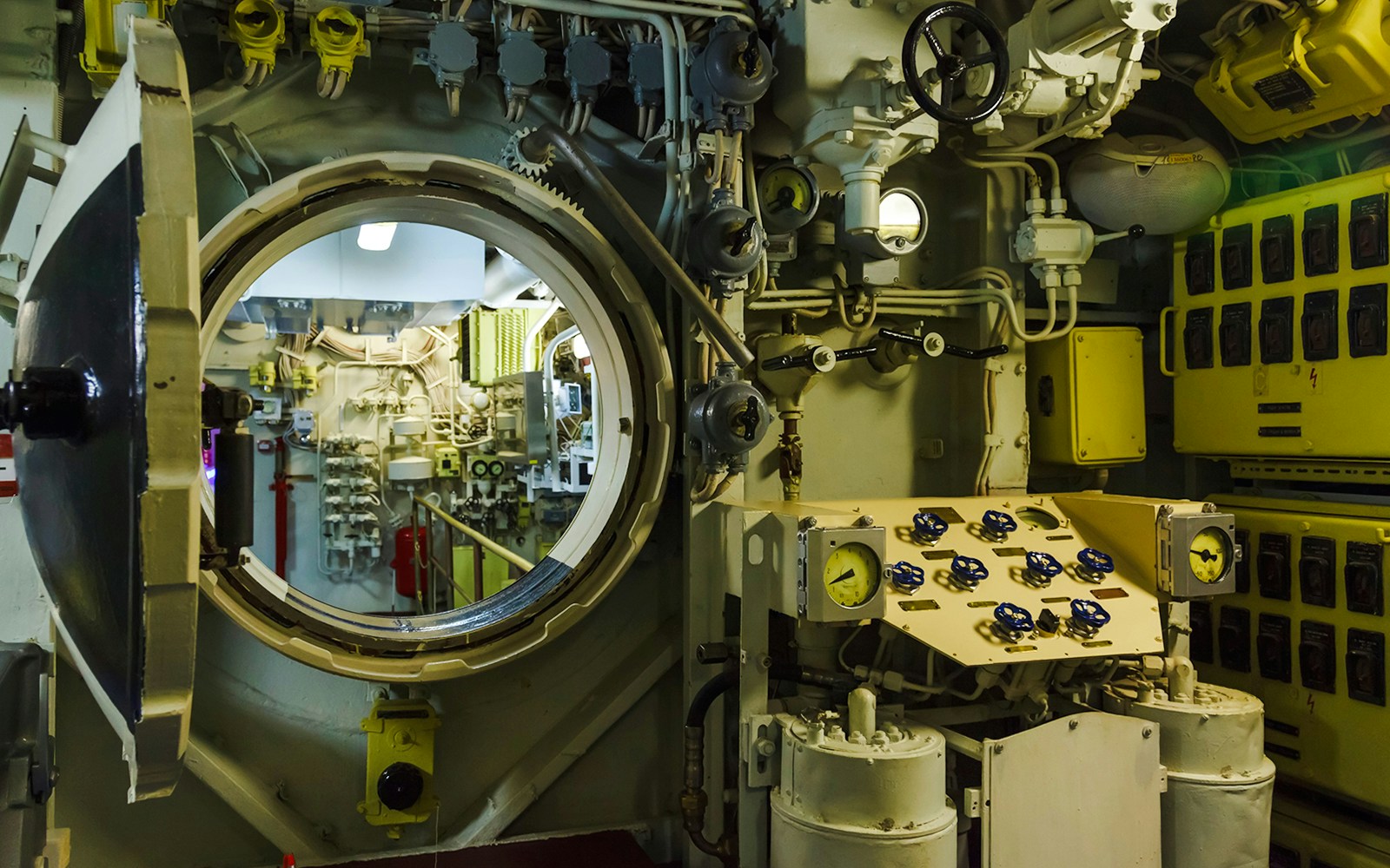 Submarine interior with control panels and open hatch.