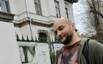 Man standing in front of Colegiul Național Școala Centrală, Bucharest, part of Spy Game tour.