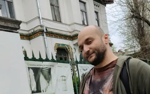 Man standing in front of Colegiul Național Școala Centrală, Bucharest, part of Spy Game tour.