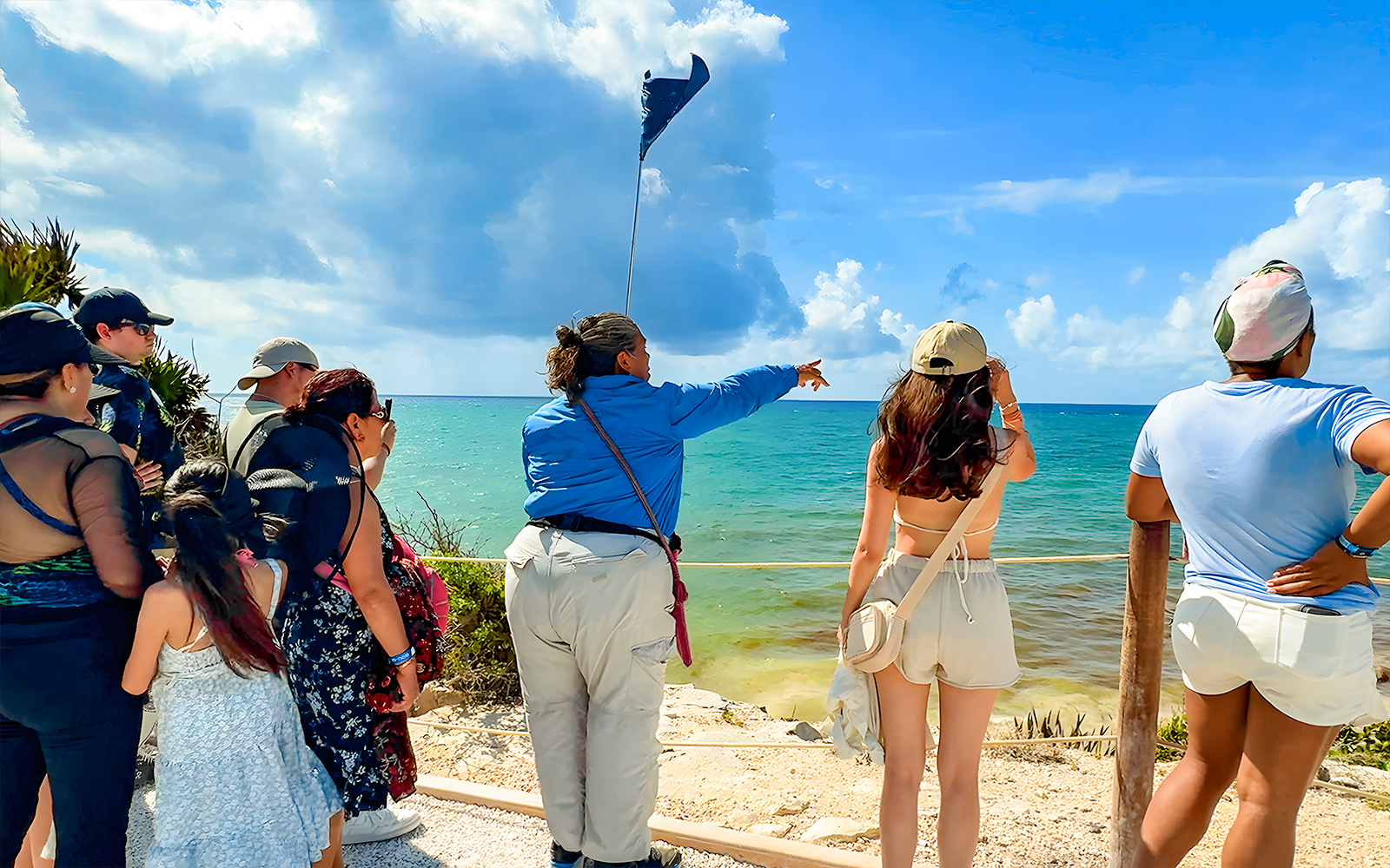 Tourist guide pointing at Tulum Beach with group of tourists.
