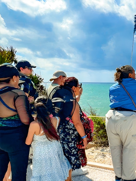 Tourist guide pointing at Tulum Beach with group of tourists.