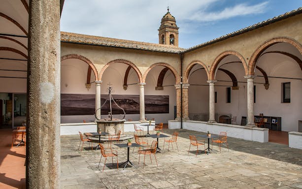 Courtyard of the Temple of Brunello in Montalcino with tables and chairs.