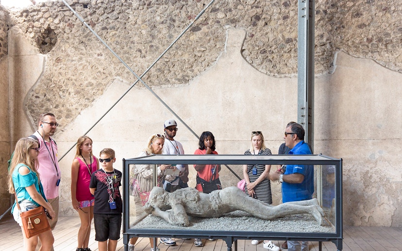 Tour guide explaining Pompeii victim cast to tourists.